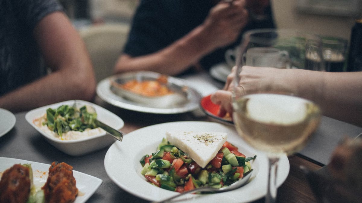 A beautifully arranged dinner setting featuring fresh salad and white wine, perfect for a fine dining experience.